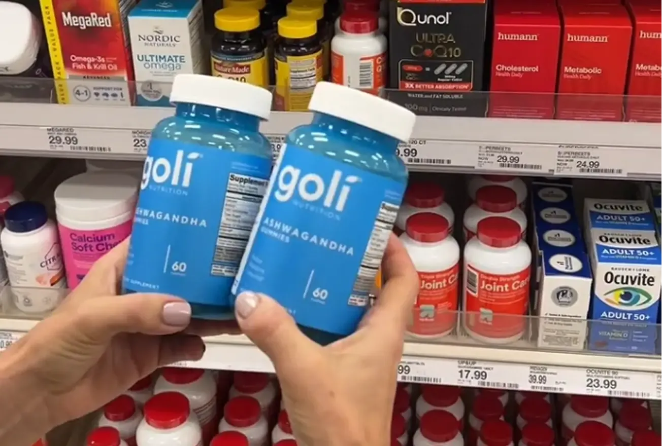 Shopper holding two bottles of Goli gummies in front of a store shelf