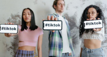 Two women and one man holding out their smartphones that display “#tiktok.”