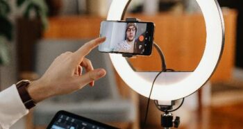 An image of a man recording a video of himself using a mobile phone.