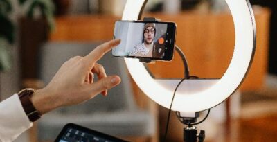 An image of a man recording a video of himself using a mobile phone.